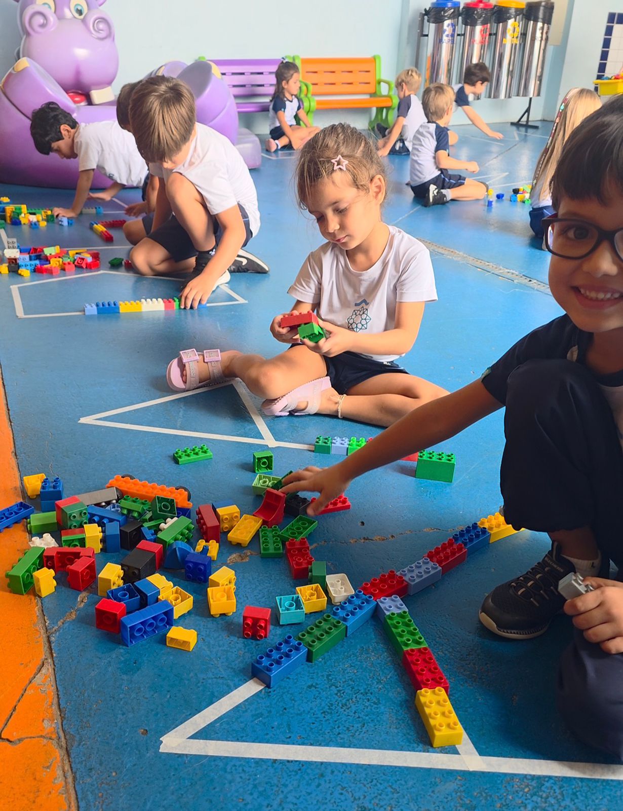Crianças da Educação Infantil percorrendo a letra inicial do nome no chão com peças de Lego no Colégio Puríssimo em Rio Claro